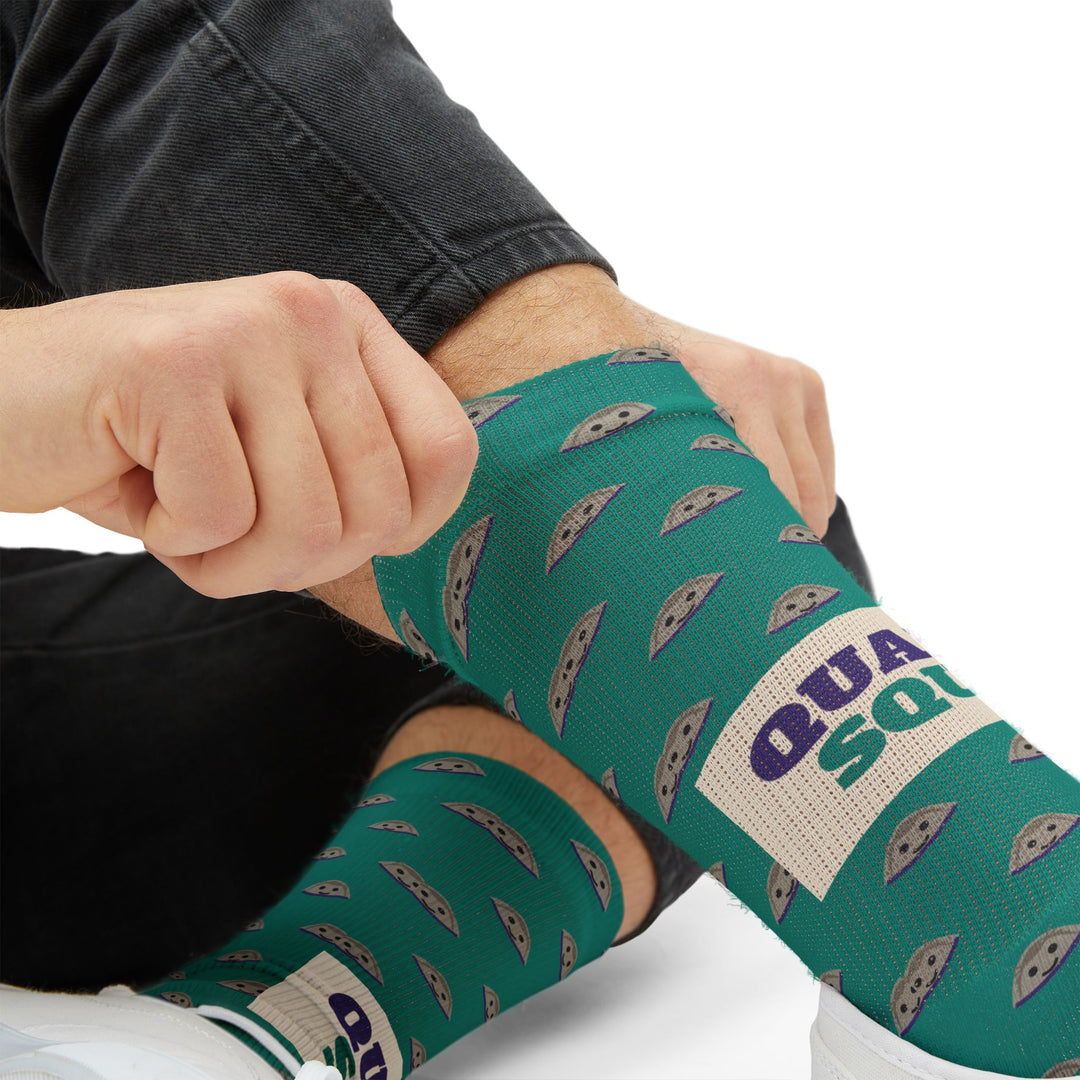 Tight close-up of a hand tugging a teal clam sock up the shin, purple Quahog Squad lettering on Rhode Island socks