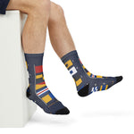 Seated with legs crossed in navy Block Island socks printed with colorful nautical signal flags