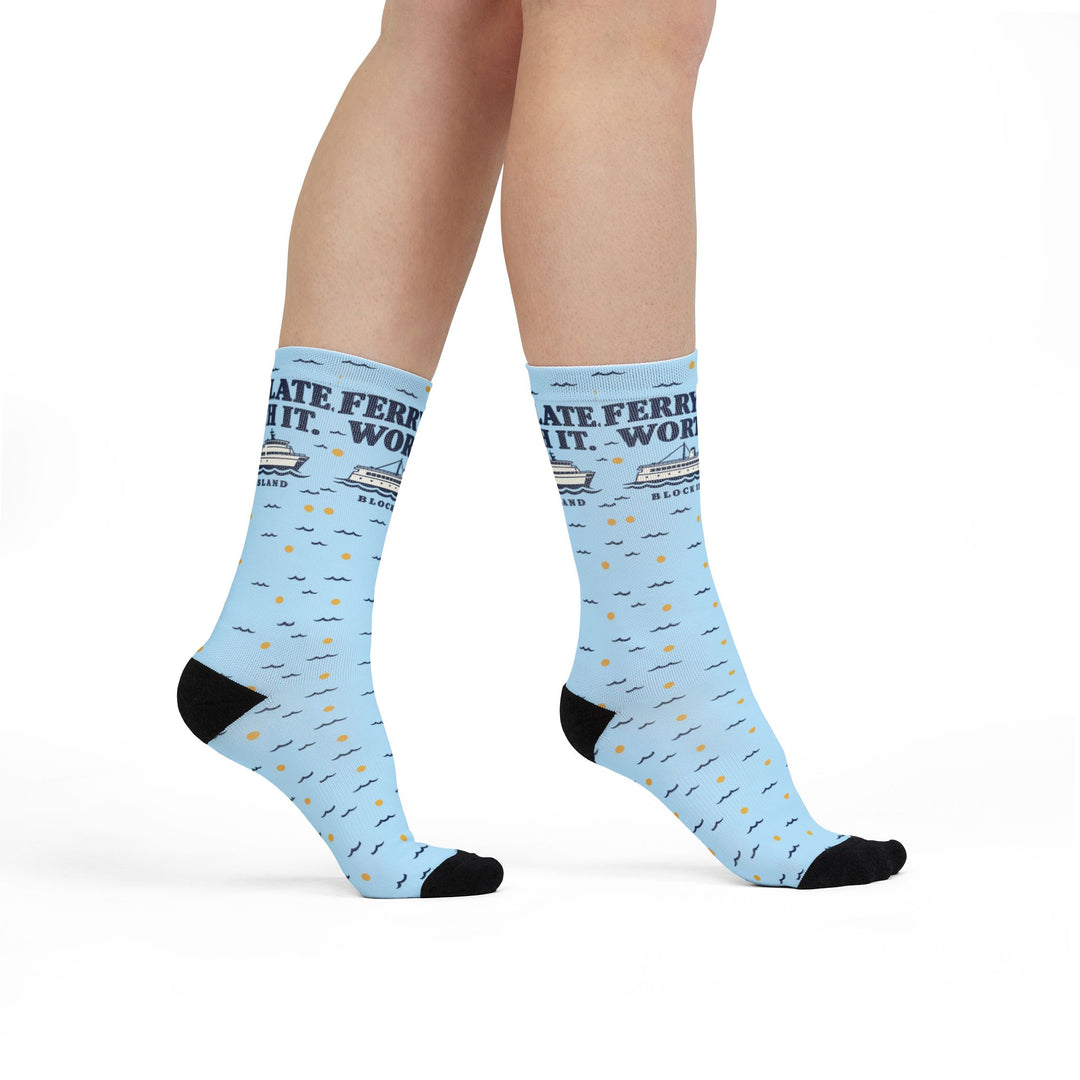 Model walking in Ferry Late. Worth It. Block Island socks, front view of the ferry graphic on light blue crew socks