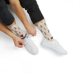 Model in jeans tying white sneakers while wearing tan Nautical But Nice nautical crew socks