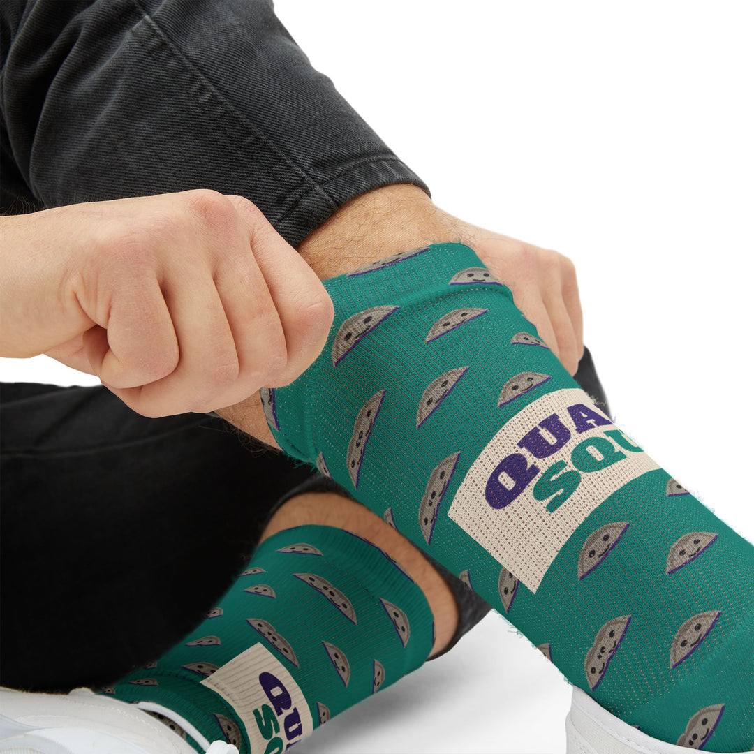 Close-up of hands pulling up a teal clam sock showing purple Quahog Squad on a cream band, Rhode Island socks