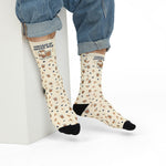 Model in rolled jeans seated on a white block wearing cream Powered by Coffee Milk funny Rhode Island socks