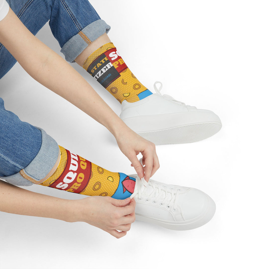 Seated model in rolled jeans tying white sneakers over yellow Squid Pro Quo calamari socks