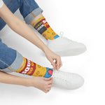 Seated model in rolled jeans tying white sneakers over yellow Squid Pro Quo calamari socks