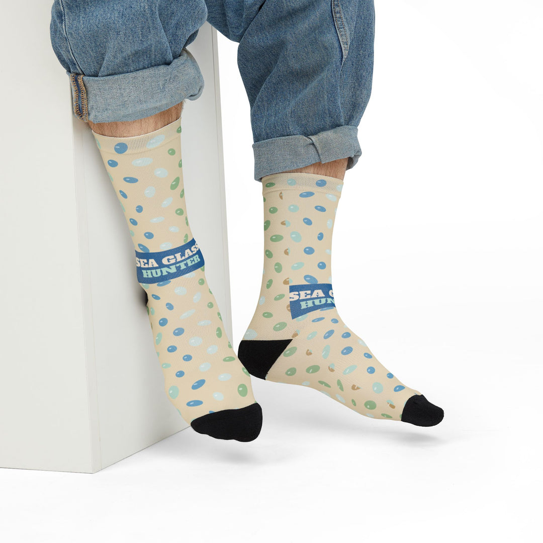 Seated model in rolled jeans showing the Sea Glass Hunter band on sand-colored coastal socks