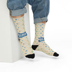 Seated model in rolled jeans showing the Sea Glass Hunter band on sand-colored coastal socks