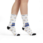 Model walking in white Rhode Island socks with gold anchors, blue ribbons and black heels and toes, side view