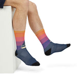 Seated model with crossed legs showing the sailboat silhouette on sunset gradient boating socks
