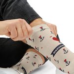 Detail of hands pulling on a tan tattoo anchor sock showing the Nautical banner and heart anchor graphic