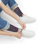 Seated model tying white sneakers in navy Property of Block Island lobster socks, a Block Island gift