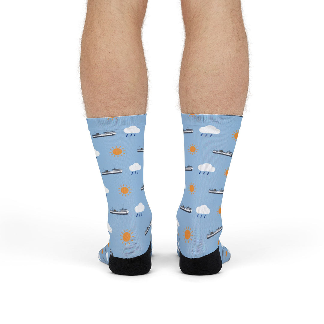 Front view of model standing in light blue funny Block Island socks with ferries, clouds and suns