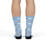 Front view of model standing in light blue funny Block Island socks with ferries, clouds and suns