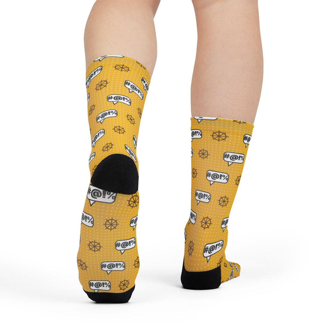 Rear view of legs in yellow nautical crew socks showing black heels and the ship wheel and grawlix pattern
