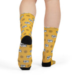 Rear view of legs in yellow nautical crew socks showing black heels and the ship wheel and grawlix pattern
