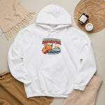 White Block Island gift hoodie laid on a wooden floor beside a woven basket, candle and dried grass