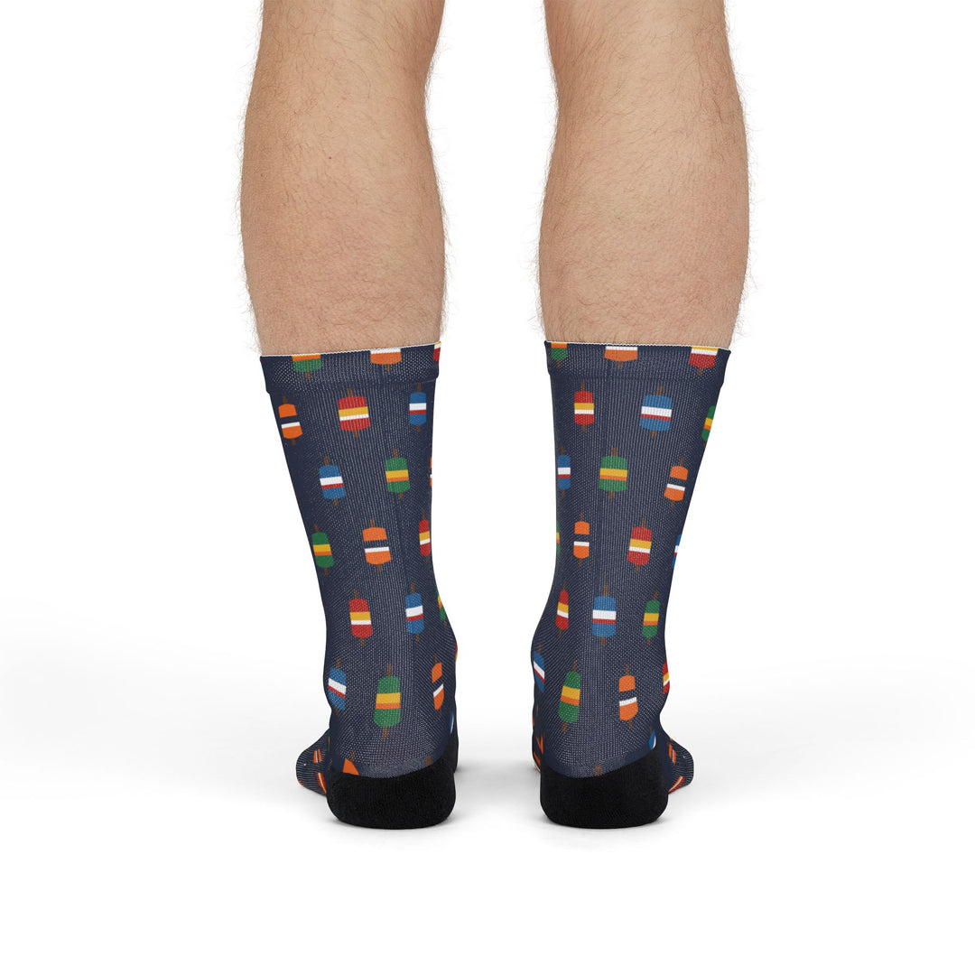 Rear view of navy Nice Buoys Rhode Island socks on a standing model, lobster buoy print down to black heels