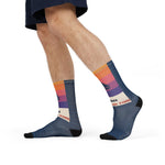 Side stride view of On Island Time sunset sail socks on a model, sailboat cuff and navy wave foot