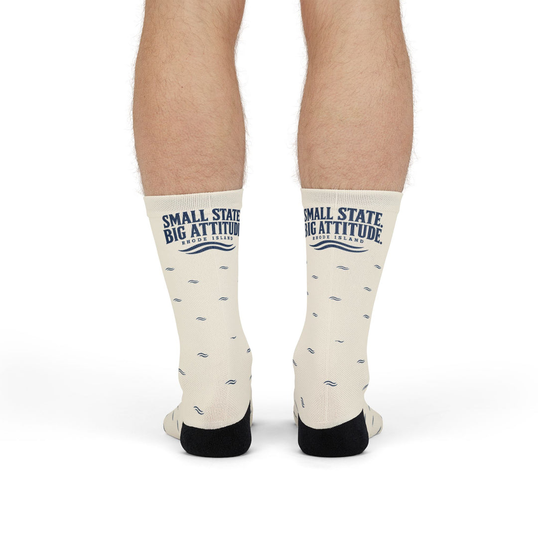 Front view of standing model wearing white Small State. Big Attitude. Rhode Island socks with navy wave print
