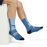Seated with legs crossed in blue Whale Hello There novelty crew socks showing the navy whale tail