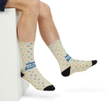 Seated side view of sand sea glass socks with blue, green and aqua glass print and black toes