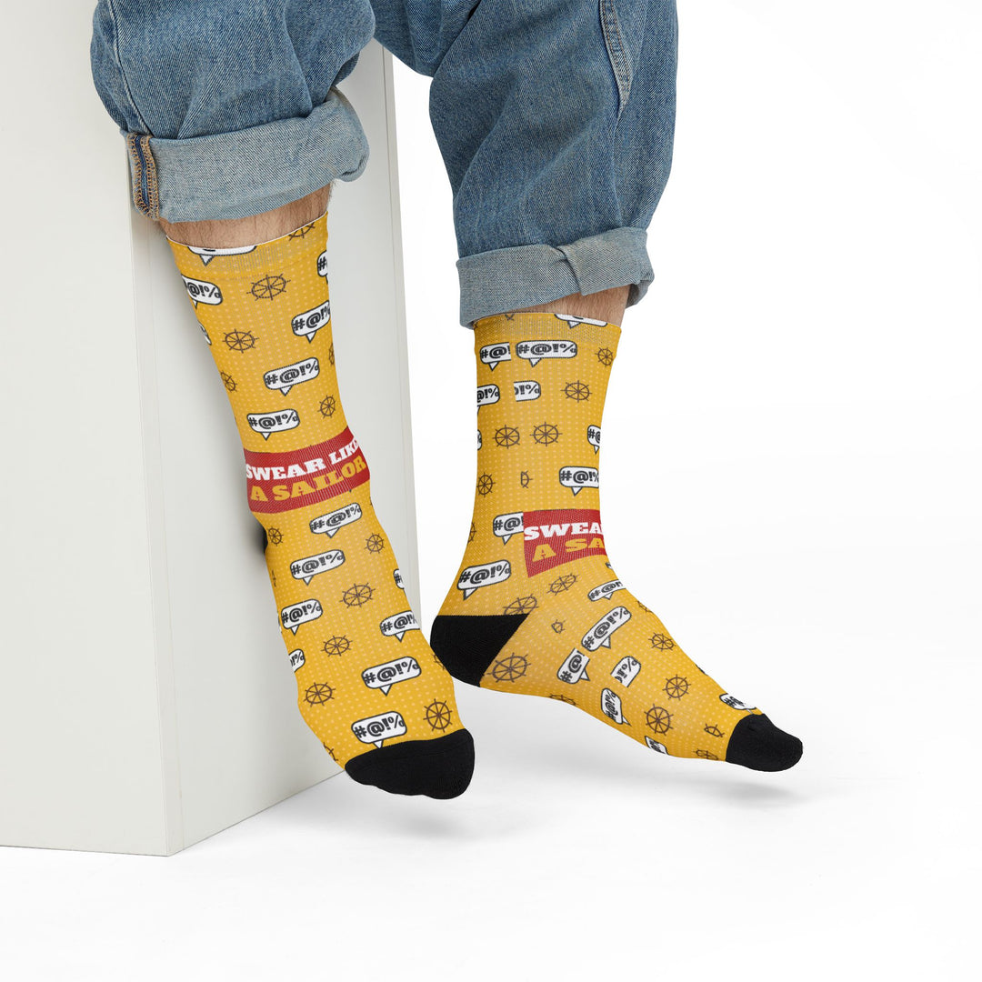 Model in rolled jeans seated on a white block wearing yellow Swear Like a Sailor nautical crew socks