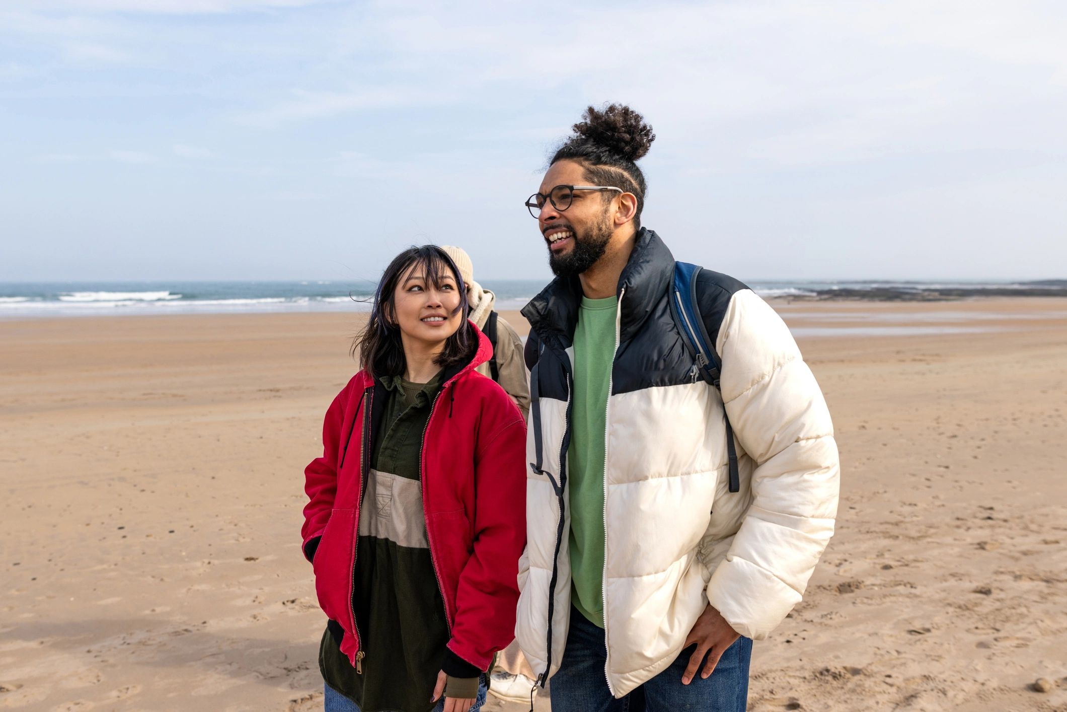 Friends in cozy coastal layers walking by the water