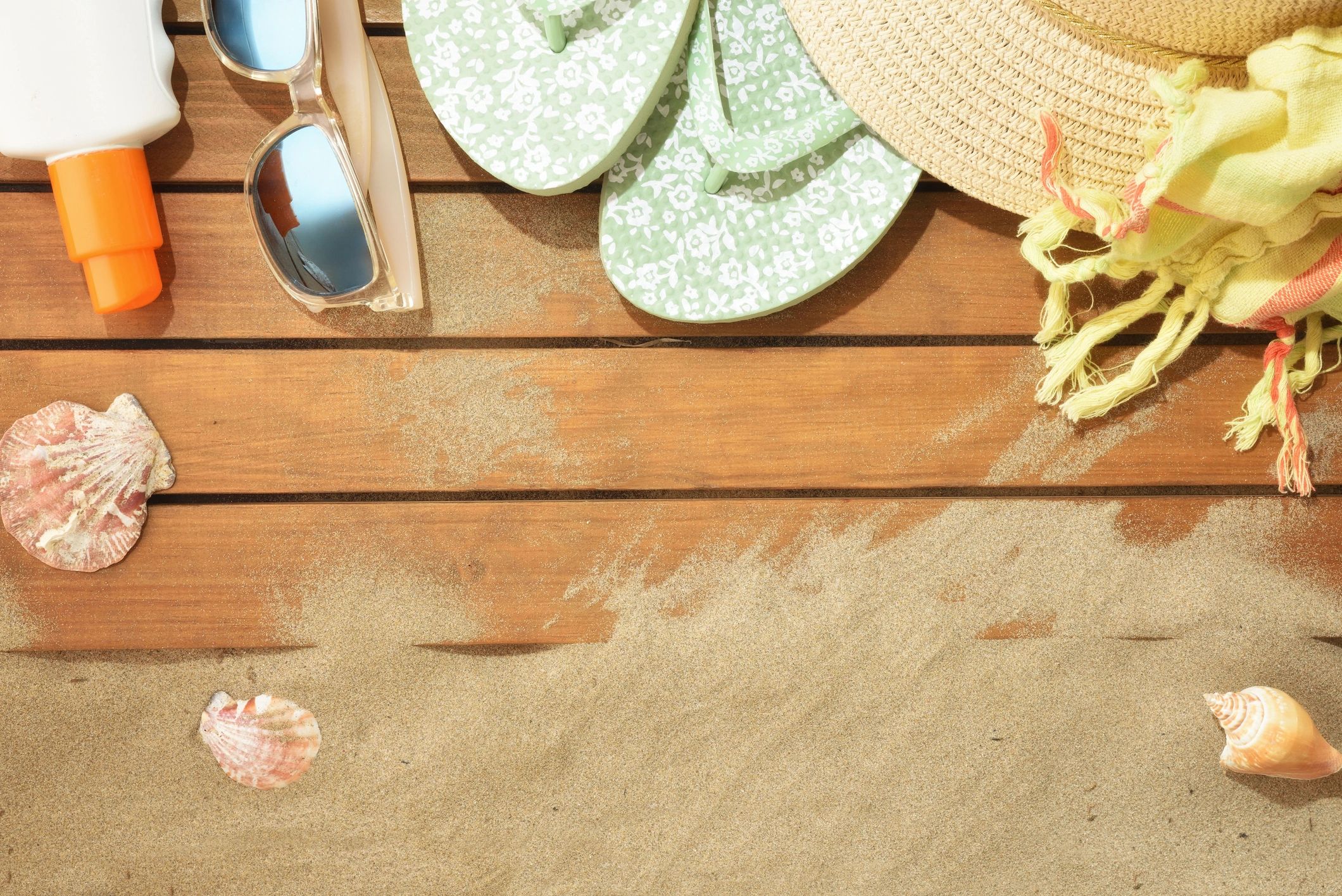 Beach accessories and apparel styled on a sandy wooden background